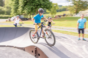 Garçon de 8 ans debout sur un VTT sur une piste de pump track (piste de VTT à bosses) - Activités terrestres