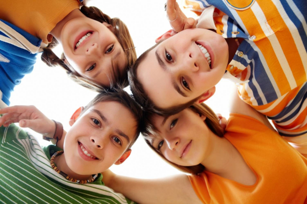 4 enfants en rond, vue d'en bas et regardant l'objectif en souriant