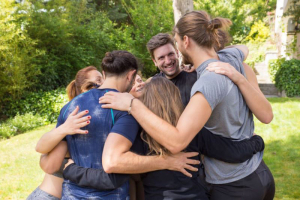 Groupe de jeunes adultes en cercle, se serrant dans les bras et rigolant