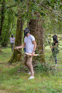 Un groupe de 3 personnes en forêt cherchant à s'atteindre avec des arcs et des flèches à embouts en mousse