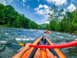 3 personnes dans un canoe gonflable dont une sur les genoux au fond de l'embarcation pour diriger.