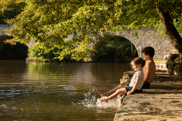 2 enfants assis au Pont du Saillant, les pieds dans l'eau et en train de rigoler