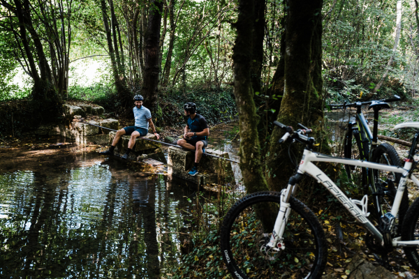 Vttiste en train de se tremper les pieds dans la Vézère pendant une activité VTT au Saillant